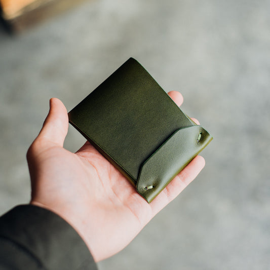 Archer wallet held by a man's hand against a blurred background.